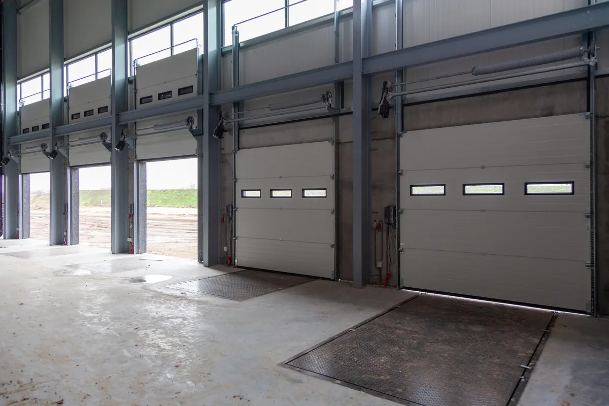 Large warehouse with a seamless high-gloss epoxy floor reflecting loading dock doors